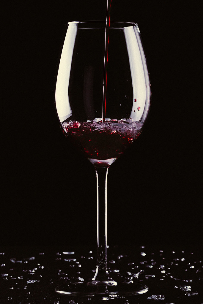 A long Stemmed Glass with Red Wine being poured into the Glass.