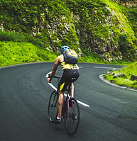 Man Cycling on Downhill Road through Luss gren Mountains.